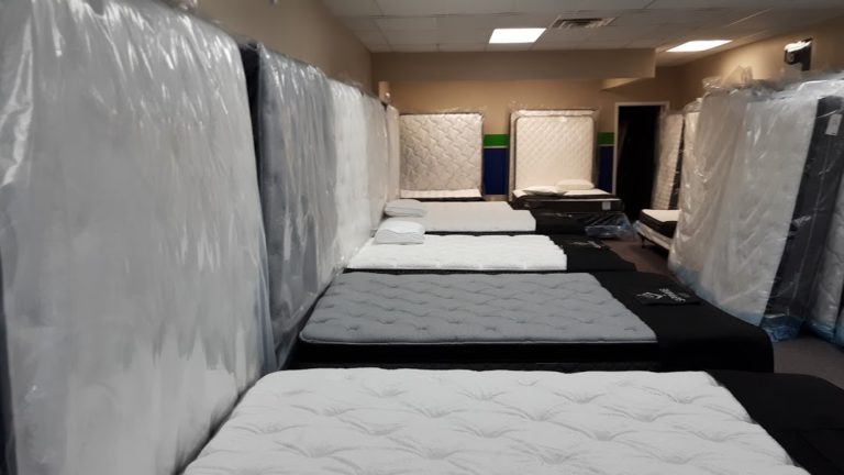 A mattress covered in plastic wrap, appearing to have been stored in a room for sale